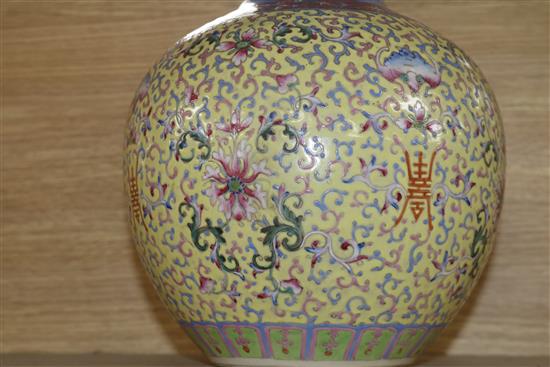 A Canton enamelled bottle vase, decorated flowers, foliate scrolls and Chinese characters on a yellow ground, height 40cm, faults